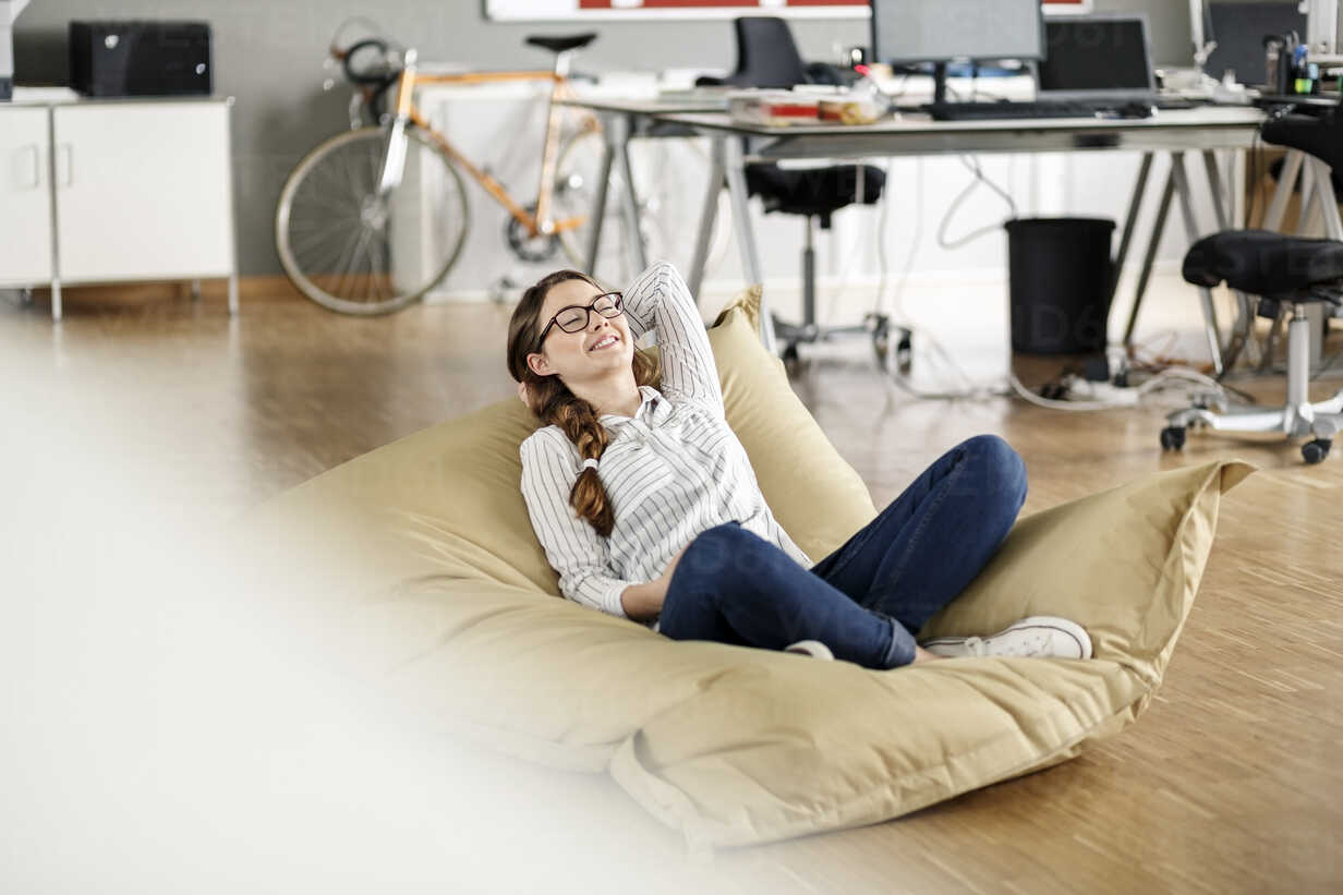 Young Woman Relaxing In Bean Bag In Office Pesf00723 Peter Scholl Westend61