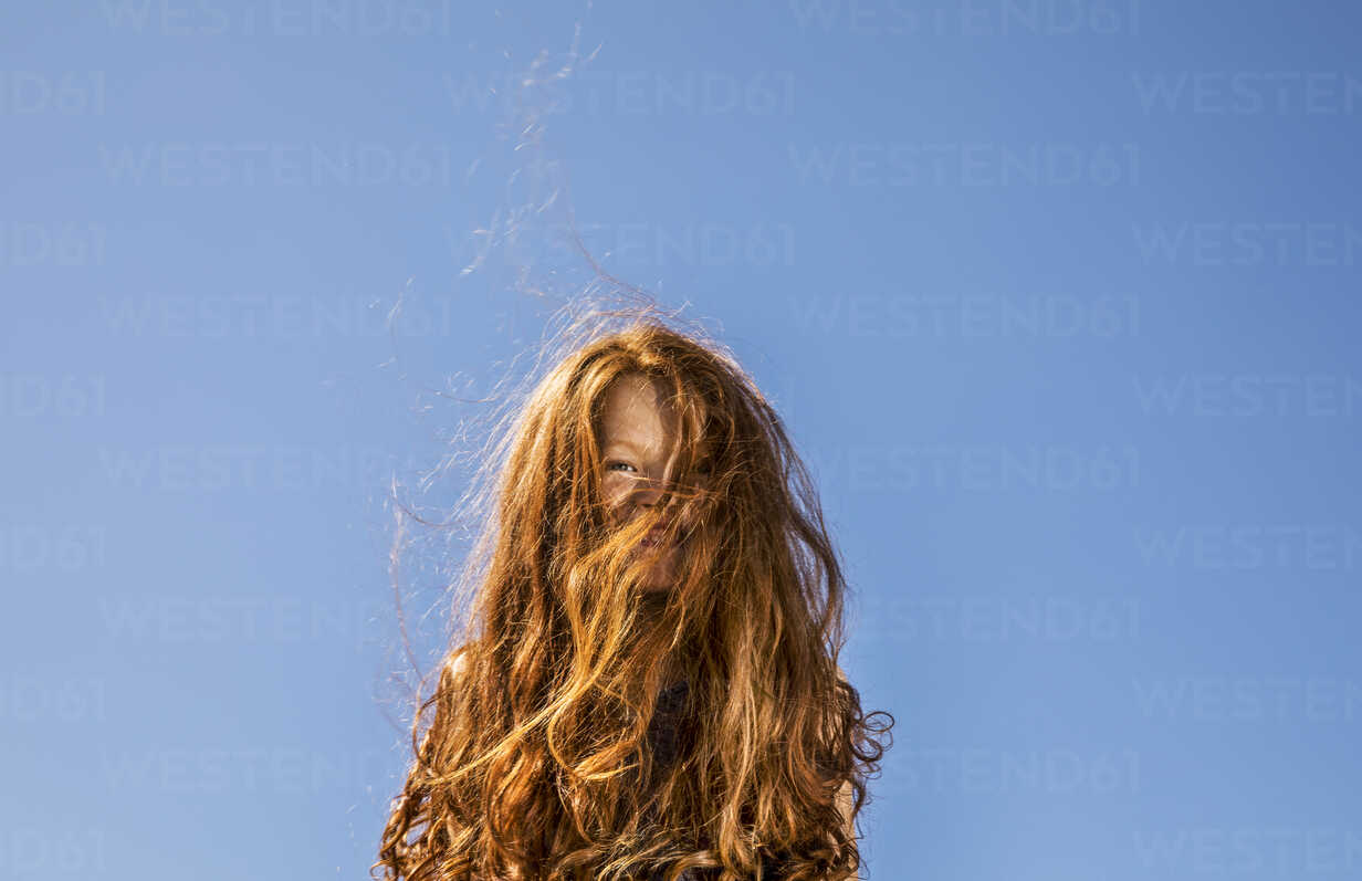 Long Red Hair Covering Face Of A Girl Under Blue Sky Stockphoto