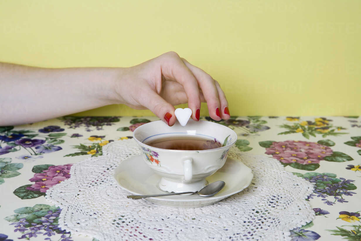 A Woman S Hand Dropping A Heart Shaped Sugar Cube Into A Cup Of Tea Stockphoto