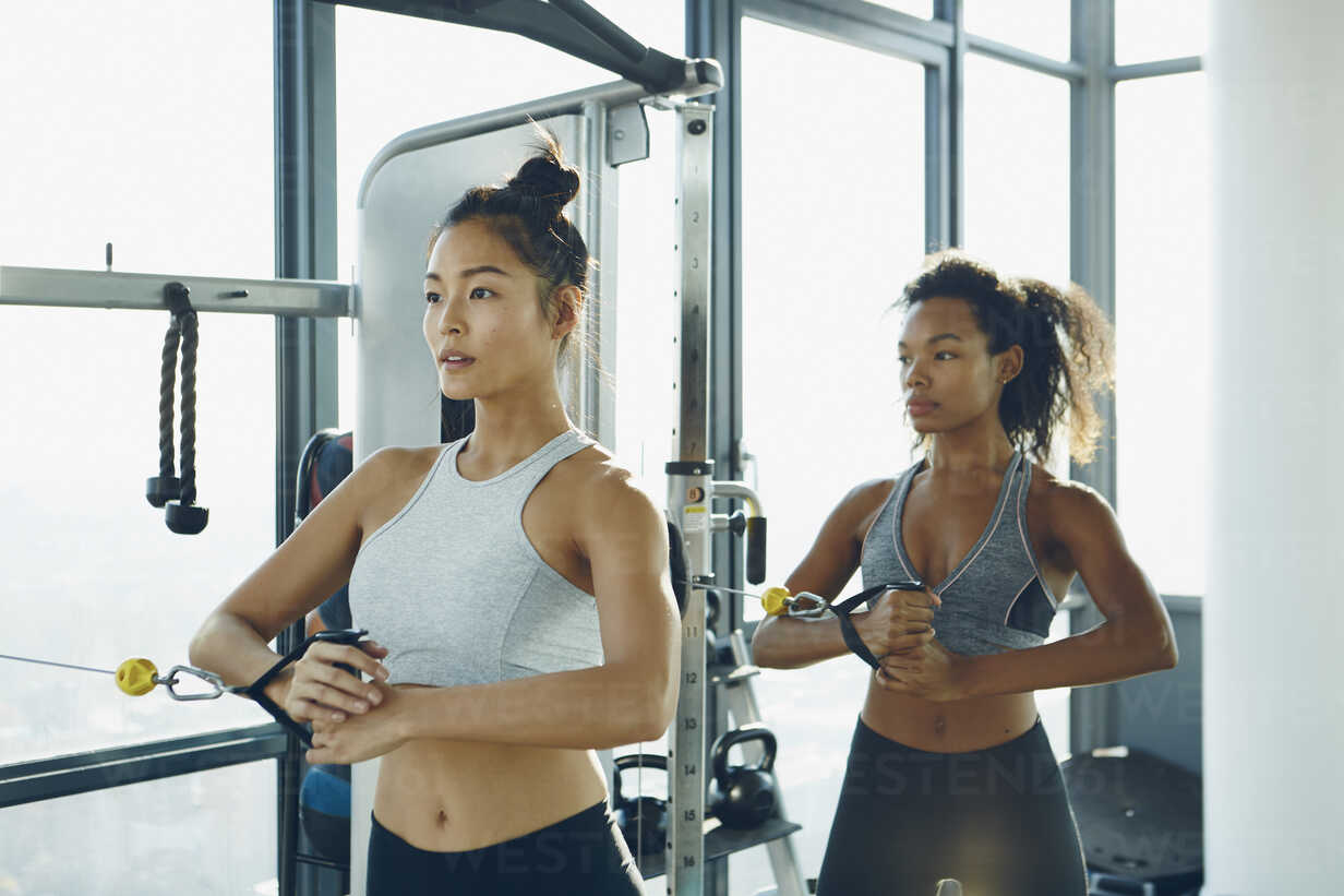 Two Young Women Working Out In Gym Using Gym Equipment Stockphoto