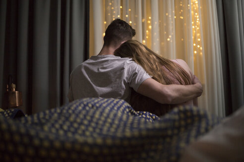Romantic Young Couple Cuddling In Bed With Fairy Lights