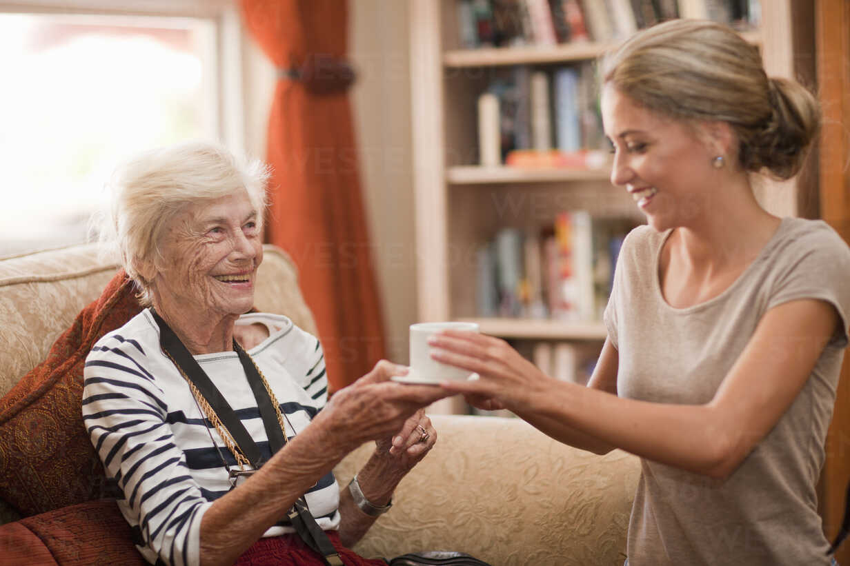 Care Assistant Handing Coffee Cup To Senior Woman Cuf Zero Creatives Westend61