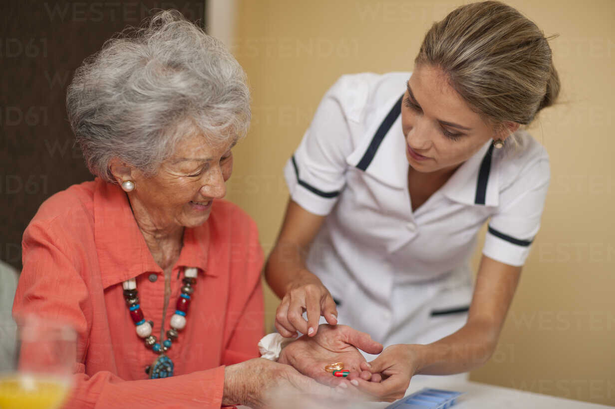 Care Assistant Handing Medication To Senior Woman Cuf Zero Creatives Westend61