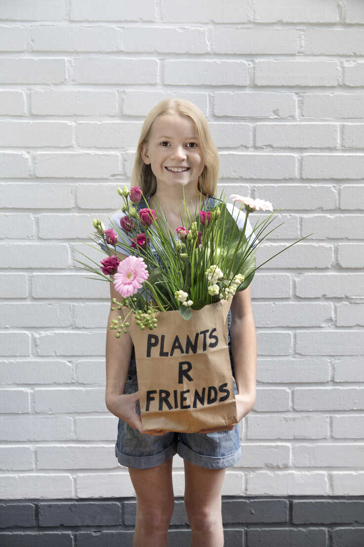 Portrait Of Smiling Girl With Paper Bag Of Flowers Stockphoto