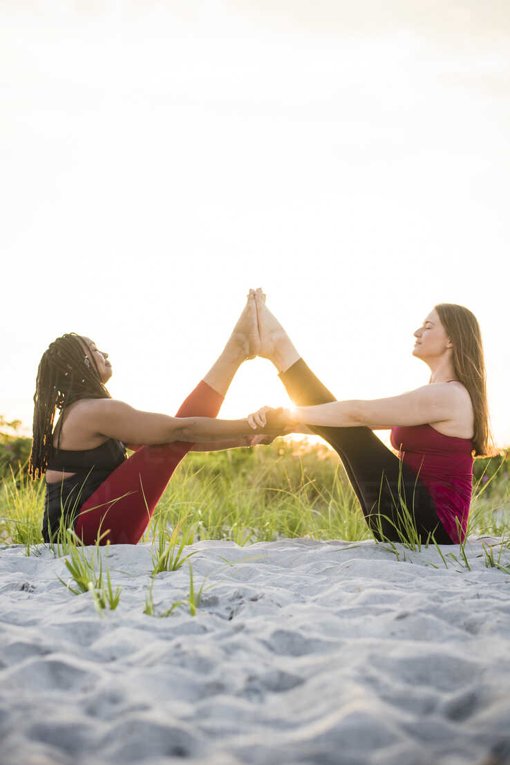 Two Women Doing Yoga In Assisted Boat Pose Navasana Newport Rhode Island Usa Stockphoto