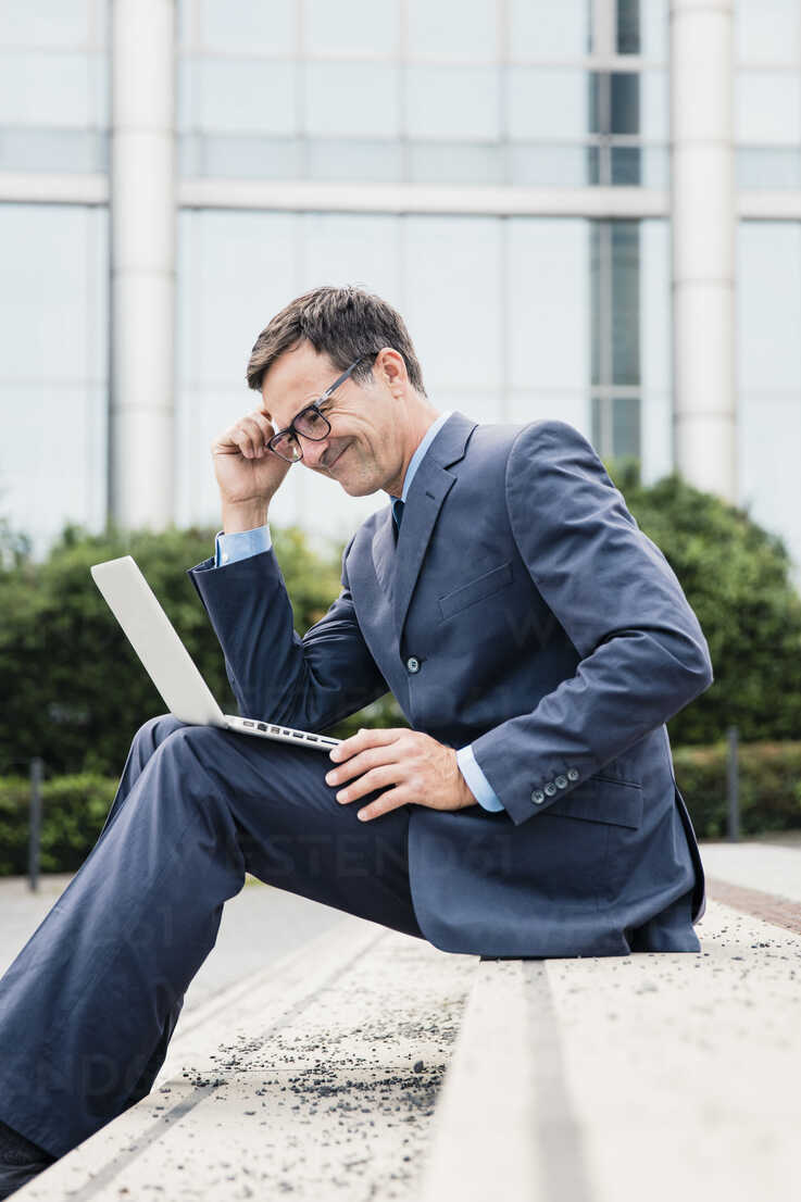 Smiling Businessman Sitting Down Using Laptop In The City Moef Robijn Page Westend61