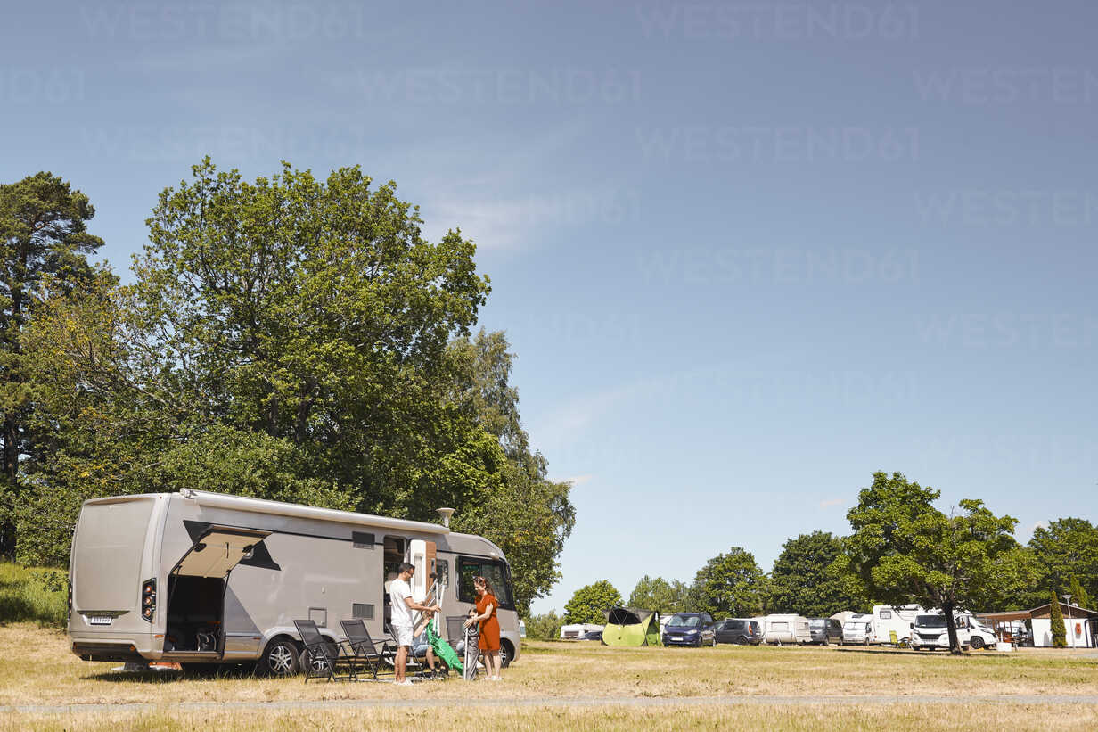 Family Arranging Chairs By Camper Van At Trailer Park Against Sky Stockphoto