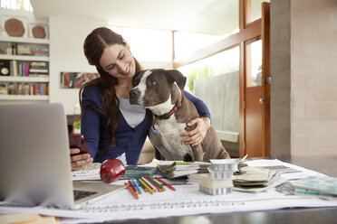 Dog Licking Face Of Female Interior Designer Working At Home