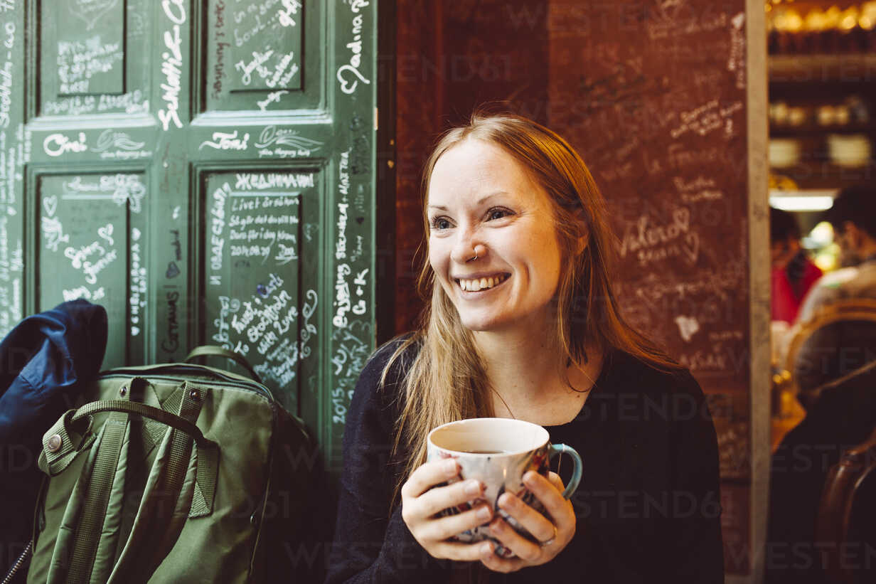 Sweden Stockholm Gamla Stan Smiling Woman Holding Coffee Cup In Cafe Stockphoto