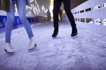 Legs Of Couple Ice Skating On An Ice Rink At Night Stockphoto