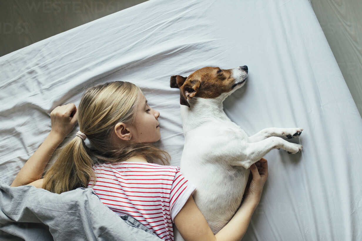 Blond Girl Lying On Bed With Her Dog Sleeping Top View Stockphoto