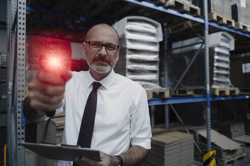 Porträt eines Mannes mit leuchtendem Scanner in einem Fabriklager - KNSF07928