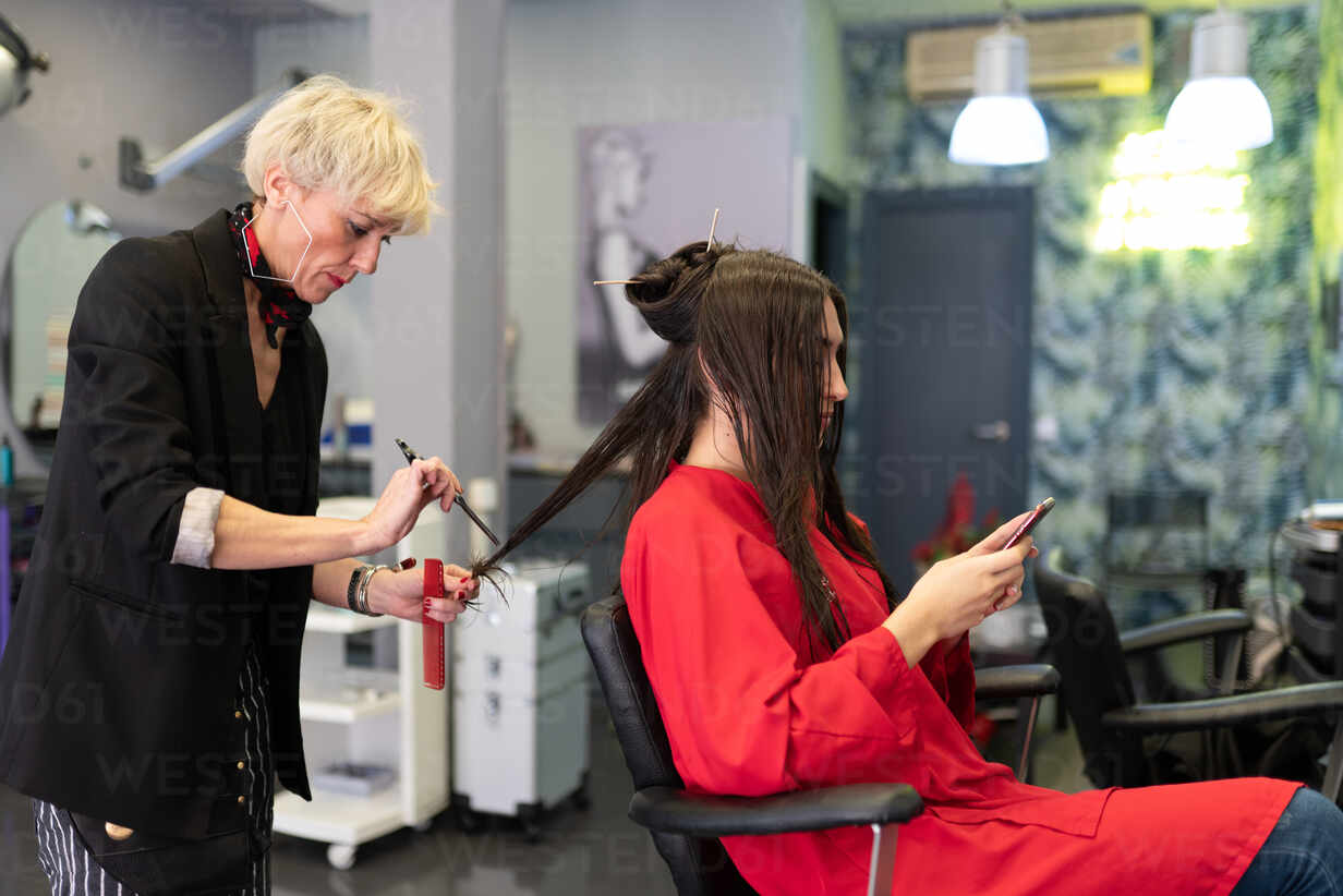 Young Woman With Mobile Phone And Sitting On Chair With Beautiful Hairstyle In Hairdressing Salon Adsf