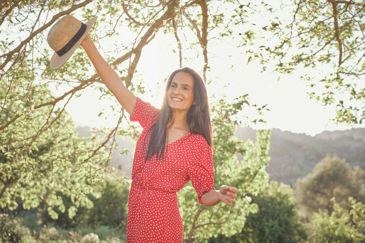 Young Attractive Cheerful Woman In Red Dress Dancing Smiling In Green Garden In Summer Day Stockphoto