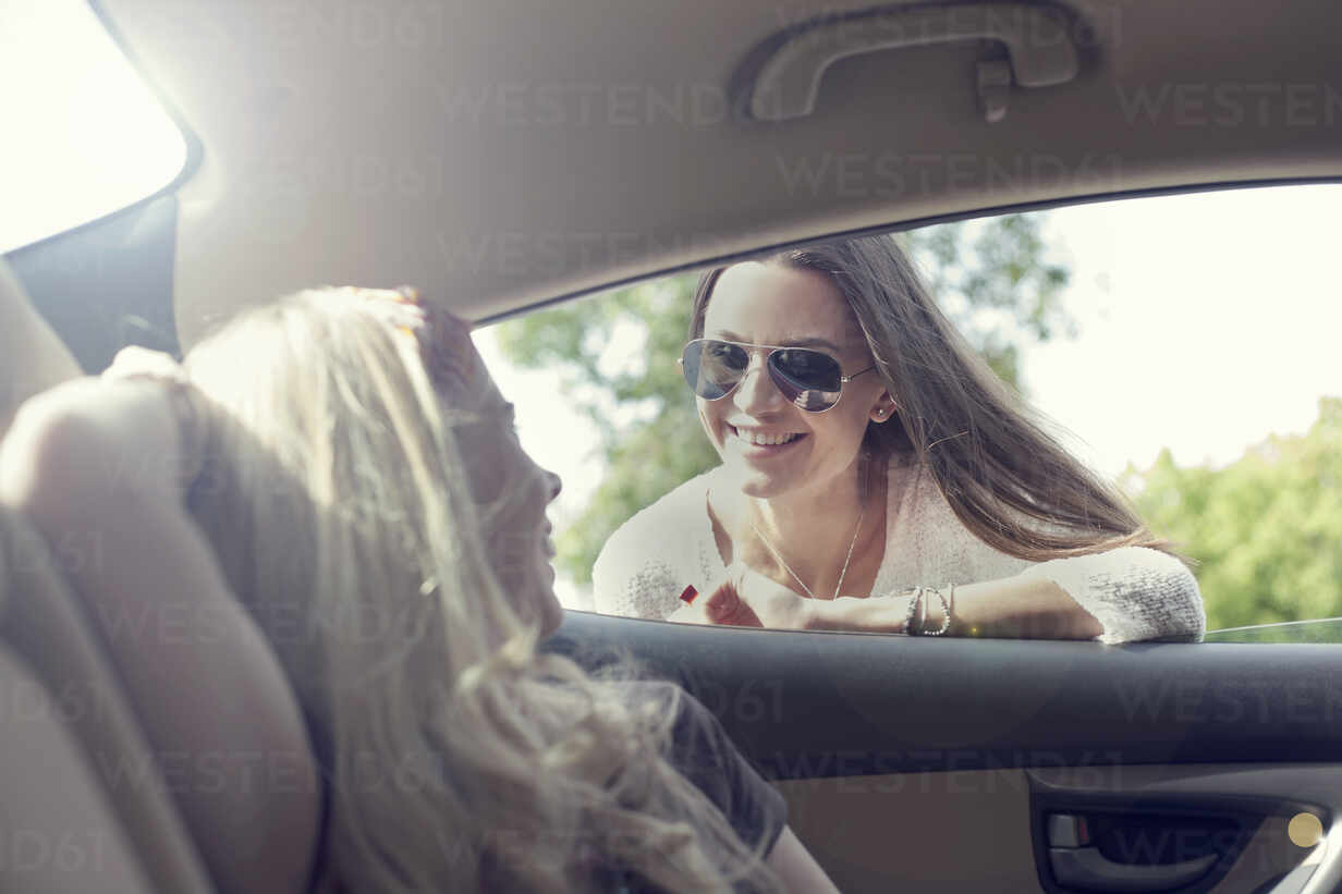 Young Woman Leaning On Car Window While Talking To Friend During Road Trip Ajof004 Louis Christian